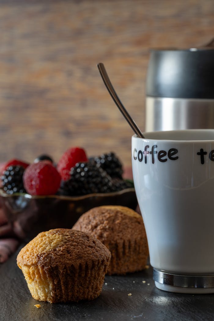 Delicious muffins with fresh berries and a steaming cup of coffee for a cozy breakfast.